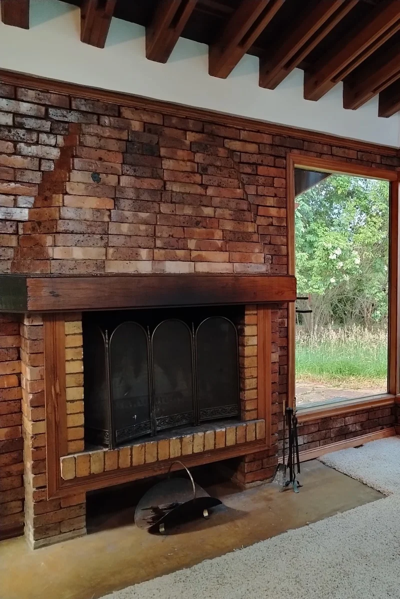 Chimenea de ladrillo con ventanal al jardín