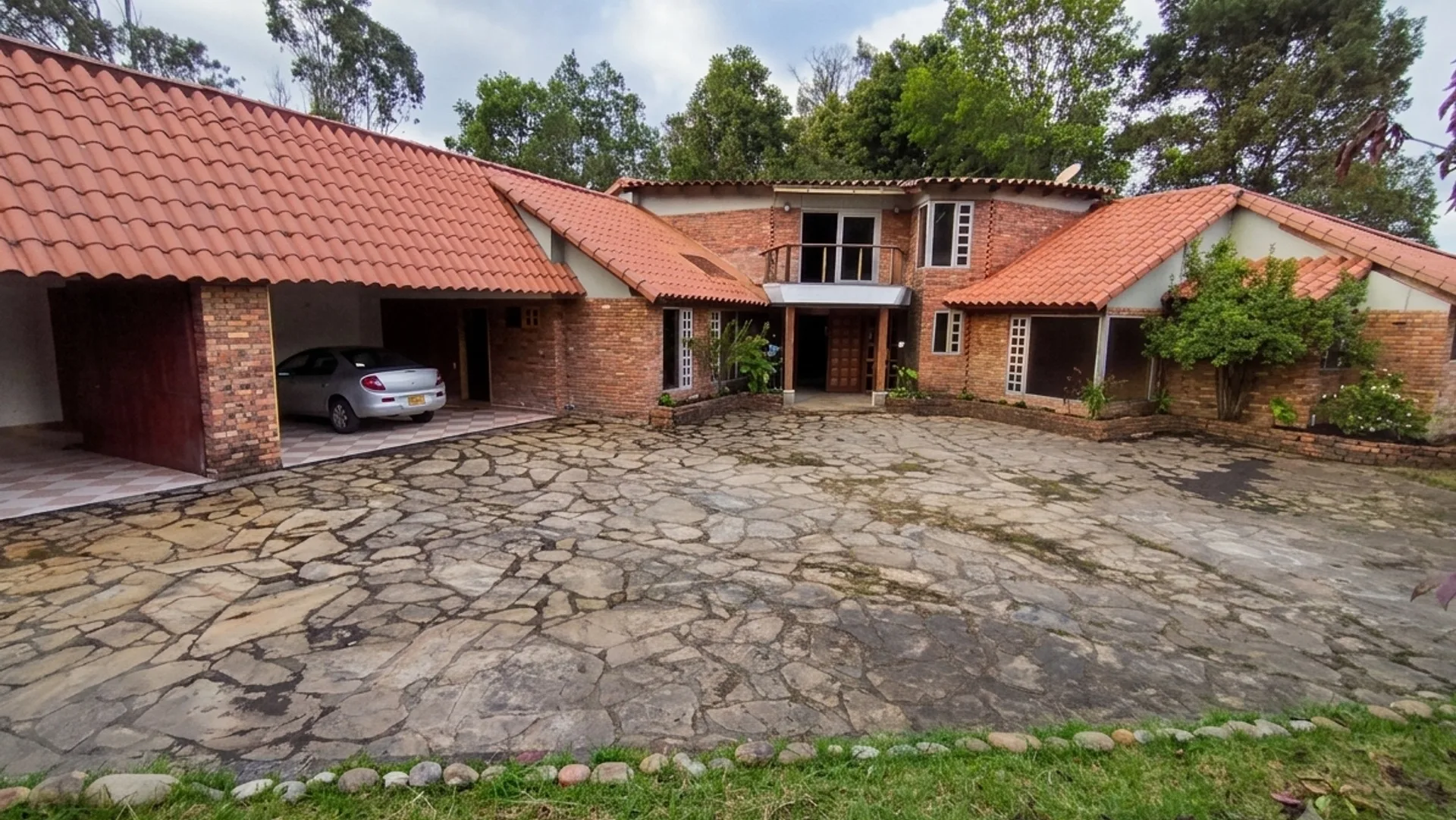 Fachada principal de La Casa Marín con techo de teja roja y patio de piedra